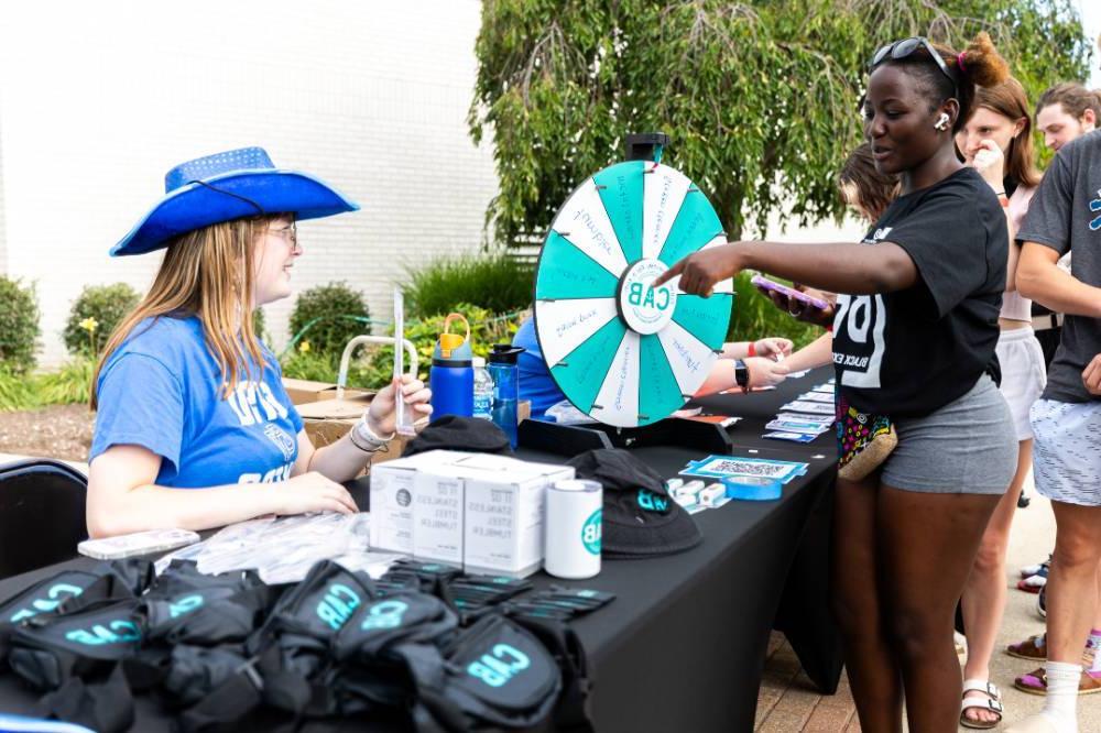 two students smiling while interacting at a table with a prize wheel